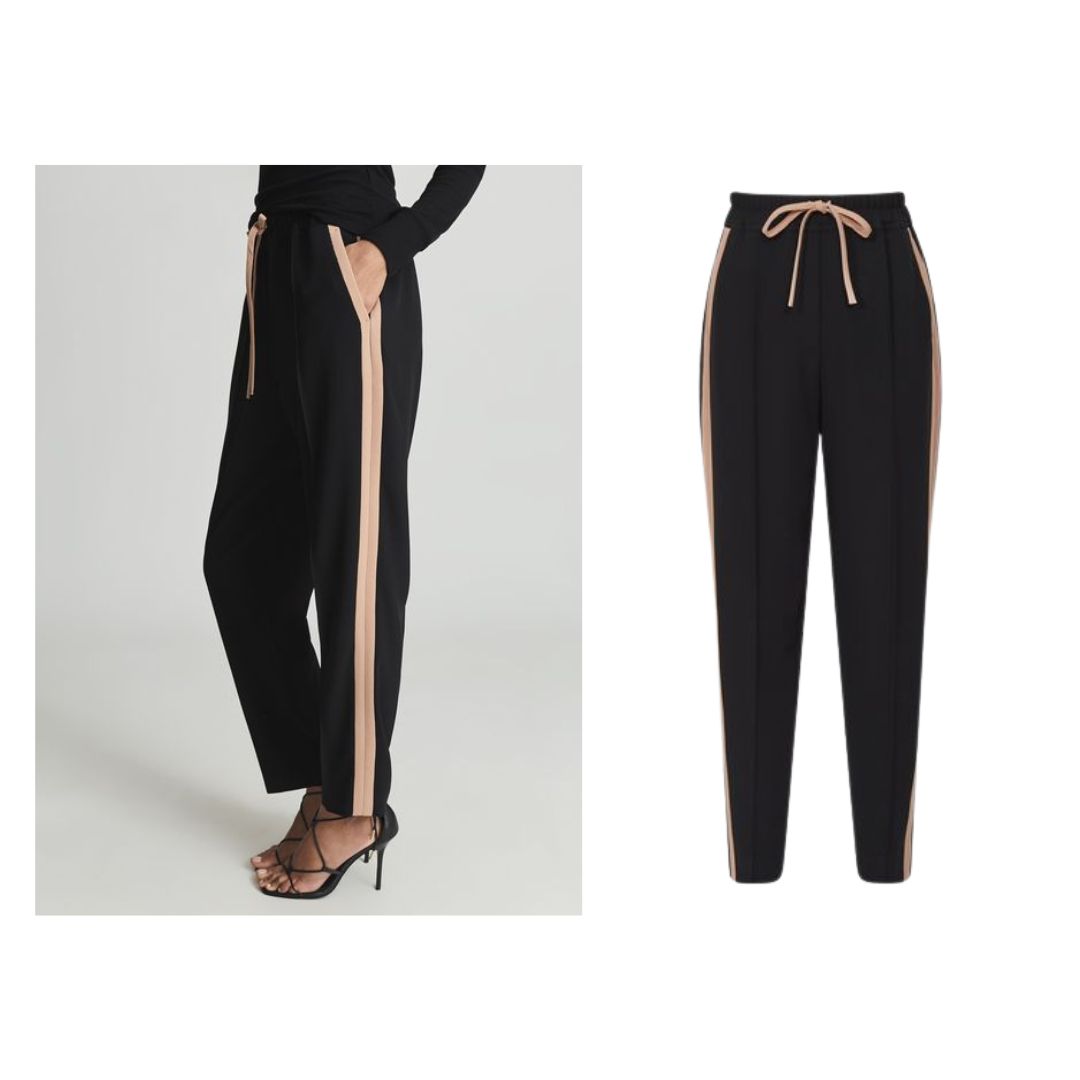 Left: Cropped photo of model wearing black drawstring waist trouser with camel coloured side stripe, worn with black sandals.
Right: Still life image of the trousers. leather jogging trouser next to still life image of faux leather jogger.